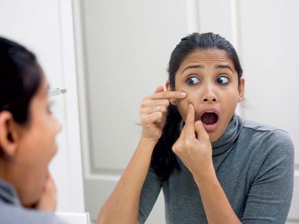 చేతితో మొటిమలను గిల్లడం